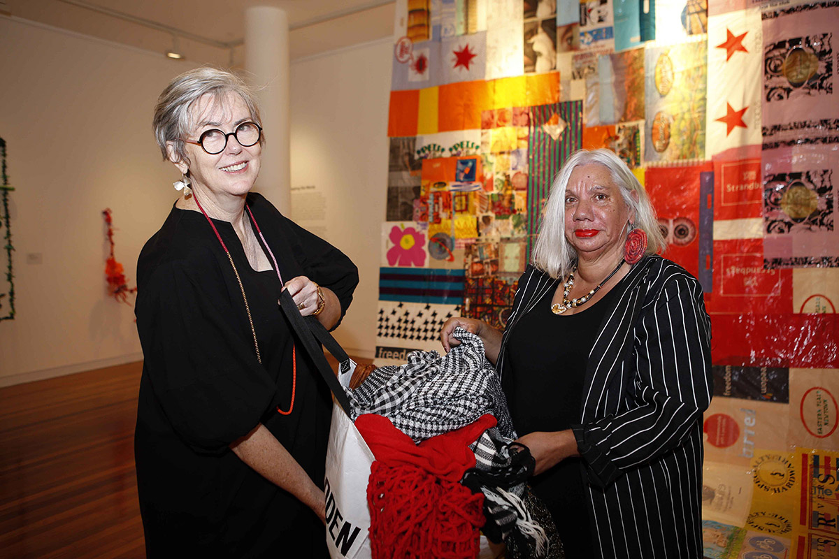 Two women looking through bag of colourful clothes at Art Gallery